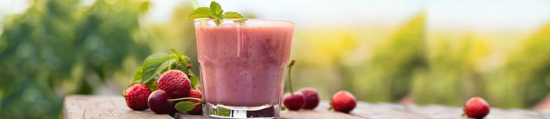 Glas mit Smoothie, Erdbeeren und Kirschen