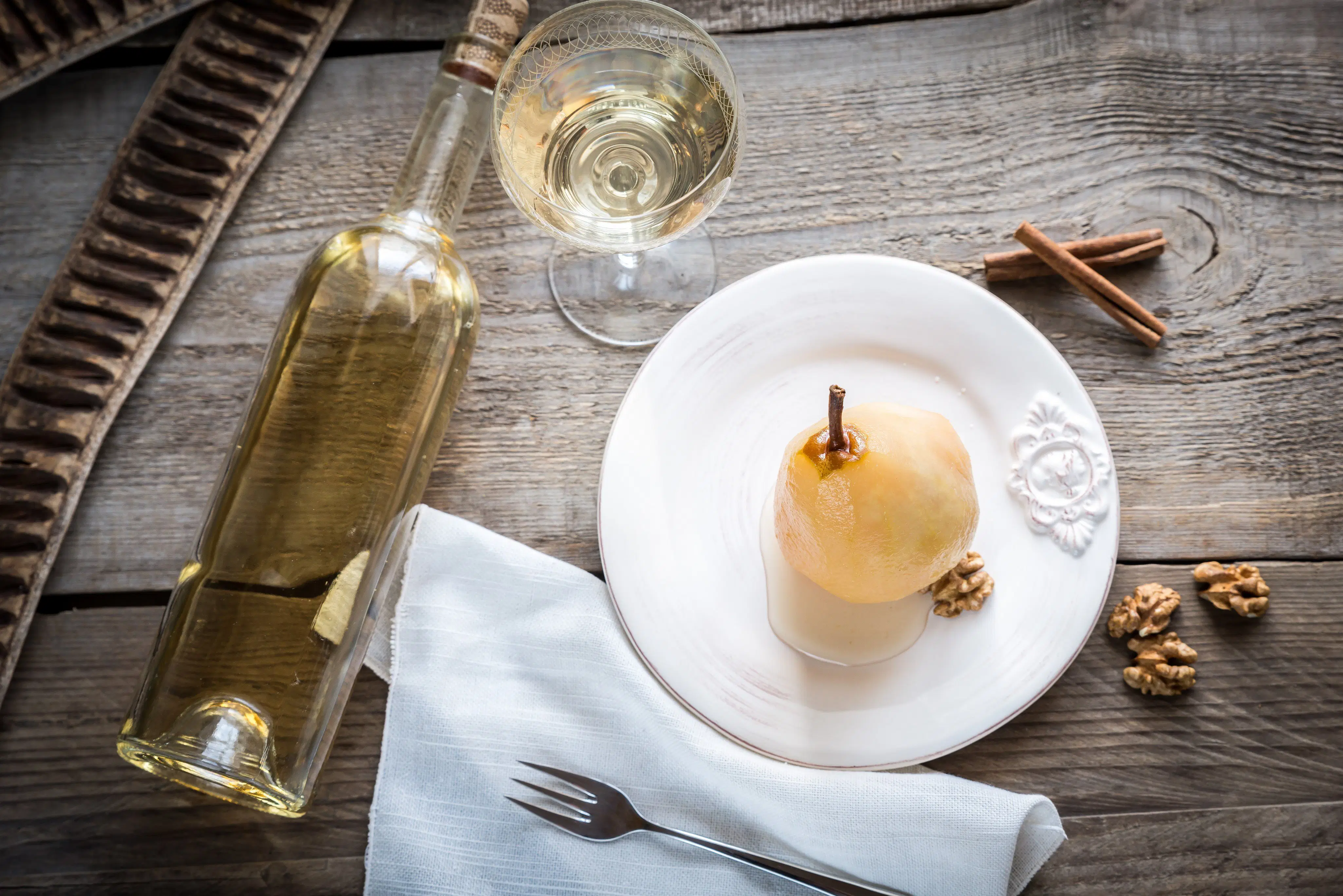 Flasche und Glas Weißwein serviert mit Birne, Walnüssen und Zimt