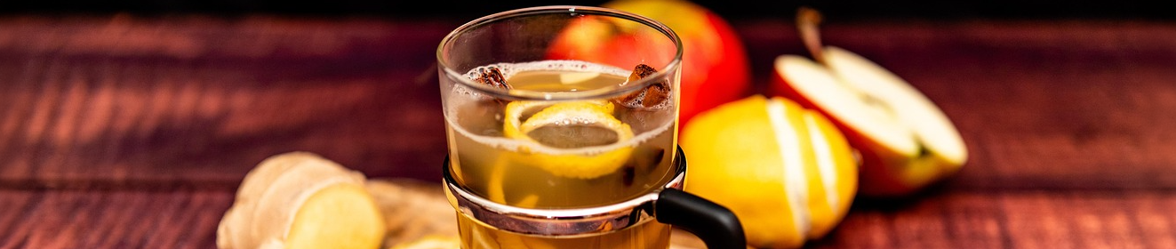 Weißer Glühwein im Glas mit Zitrone, Ingwer und Apfel